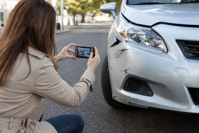 A person photographing minor car damage with a smartphone to document evidence