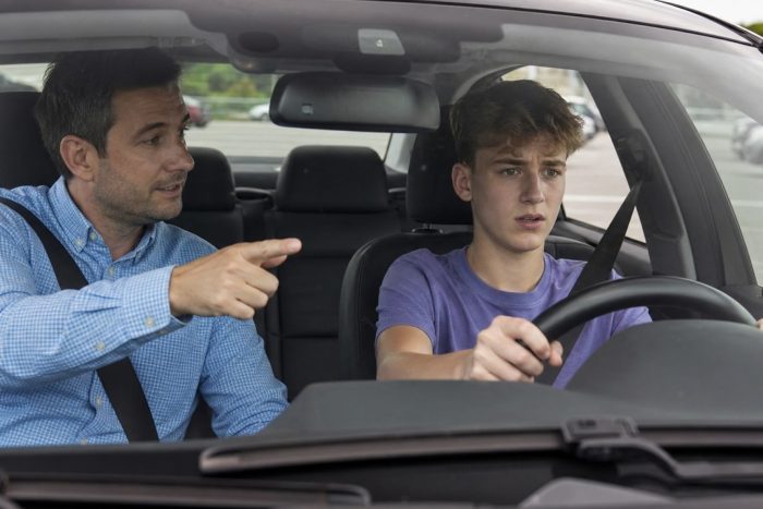 A driving instructor giving guidance to a student driver behind the wheel