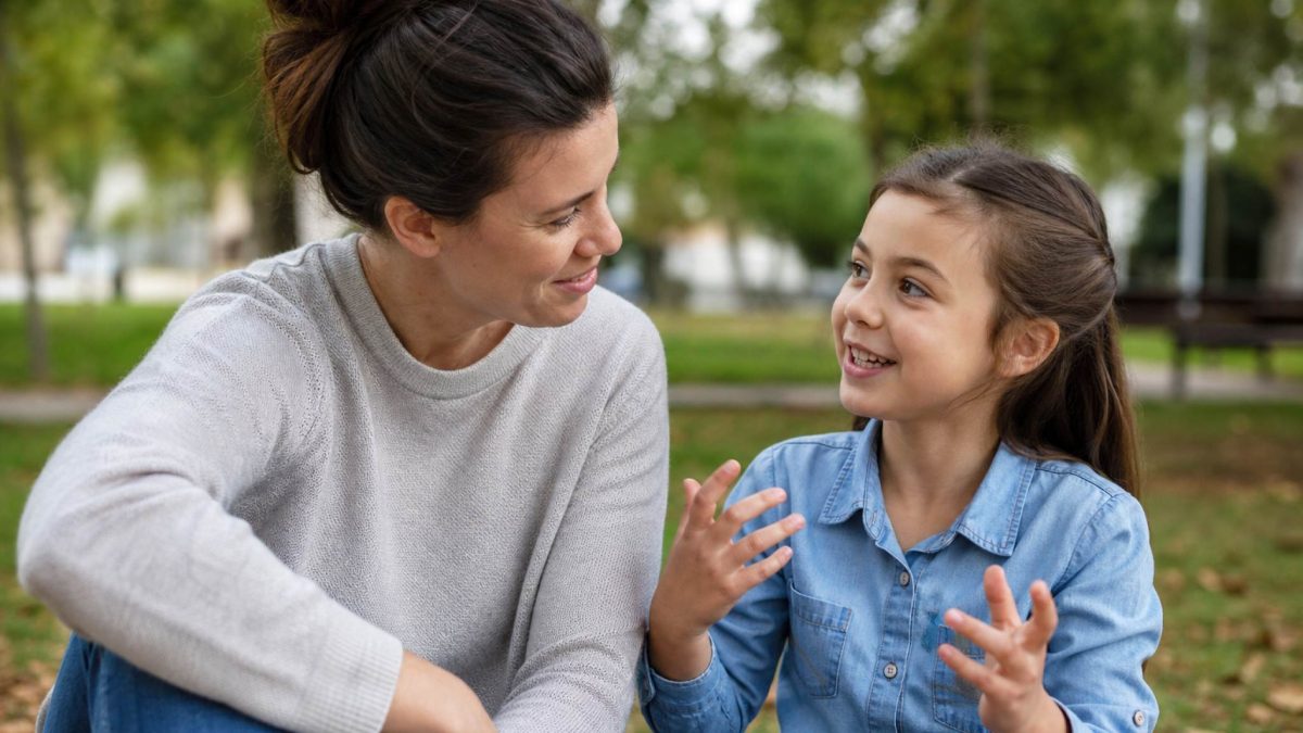 A parent attentively listening to a child speaking expressively outdoors