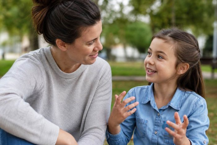 A parent attentively listening to a child speaking expressively outdoors