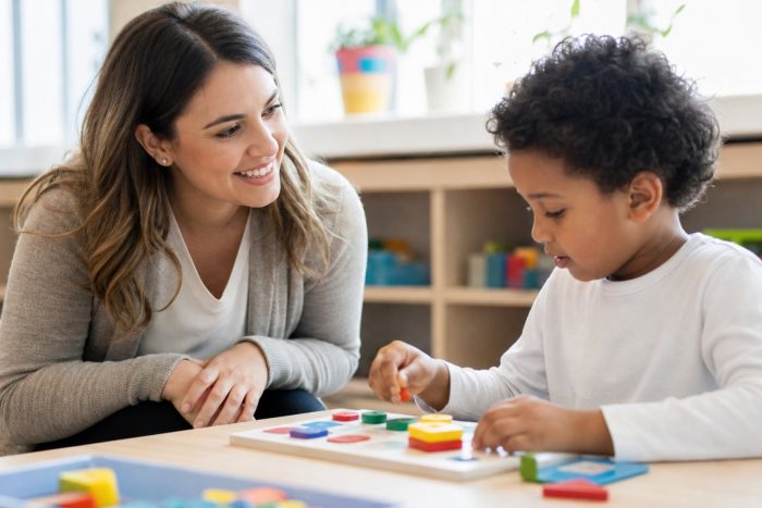 A supportive teacher smiling encouragingly while a child works on a hands-on learning task