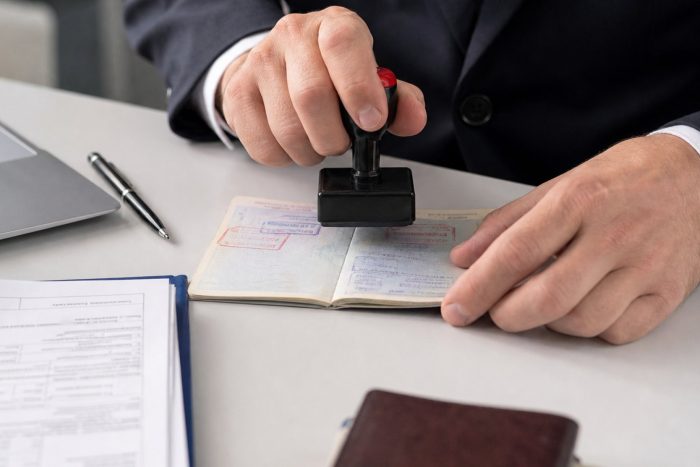 An official stamping a passport with a visa approval stamp